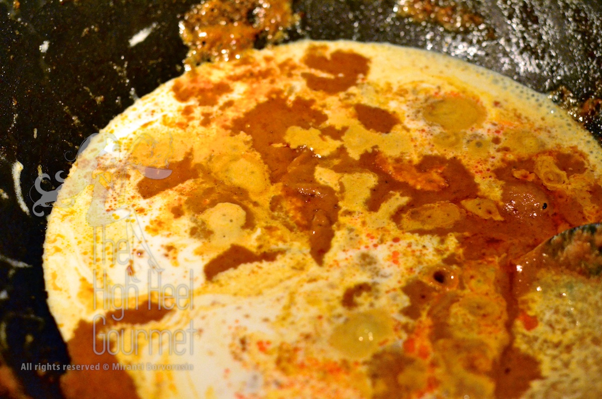 Adding more coconut cream to the edge of the wok.